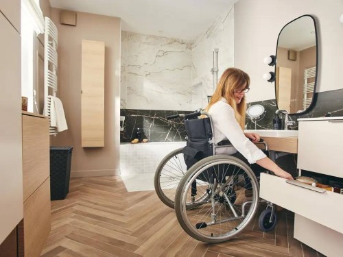 Femme en fauteuil roulant dans sa salle de bain aménagée