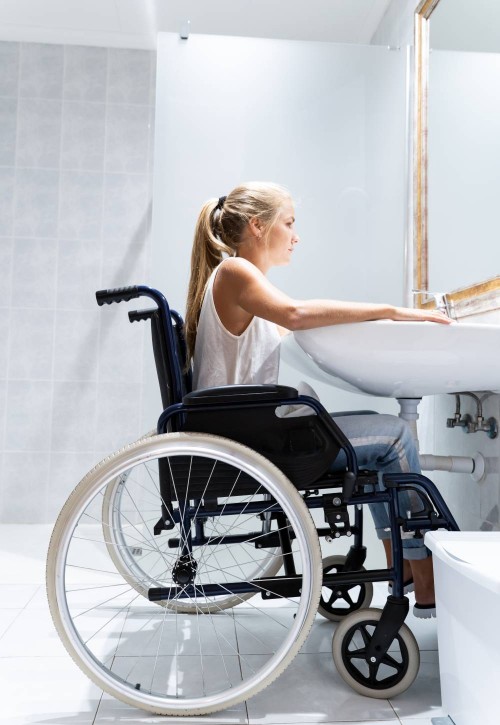 Femme en fauteuil roulant dans une salle de bain adaptée